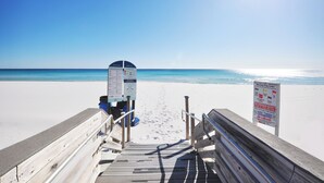 Una passerella di legno che conduce a una spiaggia con cieli sereni e acque calme.