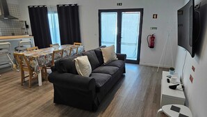 Un salon comprenant un canapé, une table à manger, des chaises et un téléviseur.