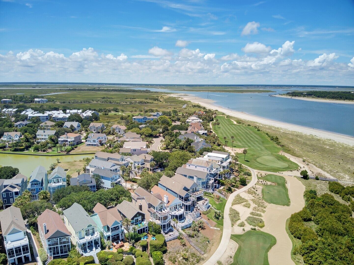 A coastal residential area with houses, a golf course, and a beach.