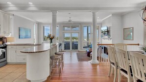 A spacious kitchen with a central island, white cabinetry, and a large window offering a view of the outdoors. - Oceanfront, Beachfront & Golf Views | 4BR in Ocean Point (Isle of Palms)