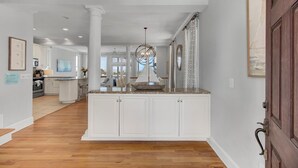 A spacious kitchen with white cabinetry, a central island, and a view to the dining area. - Oceanfront, Beachfront & Golf Views | 4BR in Ocean Point (Isle of Palms)