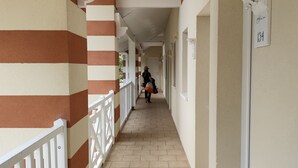 A corridor with striped walls, a tiled floor, and a white railing.