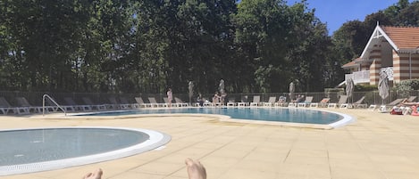 A pool area with lounge chairs and a building in the background.