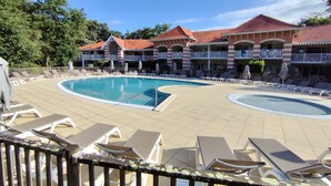 A pool area with lounge chairs and a building with a red-tiled roof.