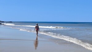 A beach scene with a person walking along the shore.