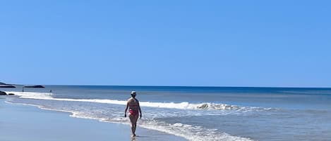 A beach scene with a person walking along the shore.