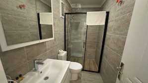 A modern bathroom with a bathtub, toilet, and glass shower enclosure. - Noa Ayvalık Guest House (Ayvalik)