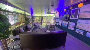 A cozy indoor seating area with a sofa, tables, and chairs, surrounded by decorative plants and artwork. - Gulfport Beach Home By Casino (Gulfport)