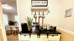 A kitchen area with a coffee bar sign, a coffee maker, and mugs on the counter. - Gulfport Beach Home By Casino (Gulfport)