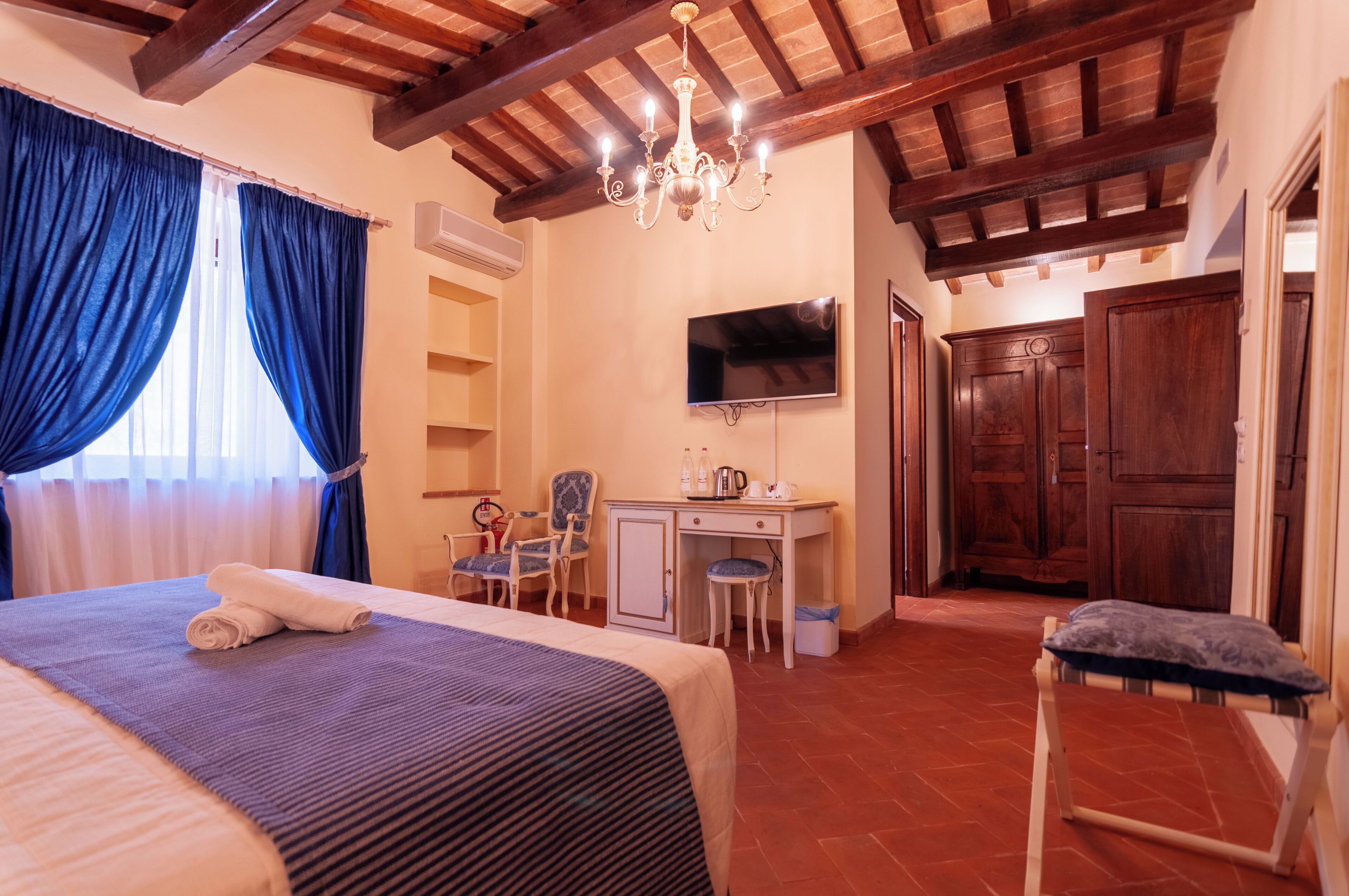 A hotel room with a bed, a desk, a TV, and a wardrobe.
