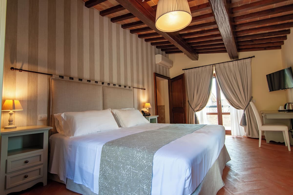 A hotel room with a large bed, two bedside tables with lamps, a desk, and a TV.