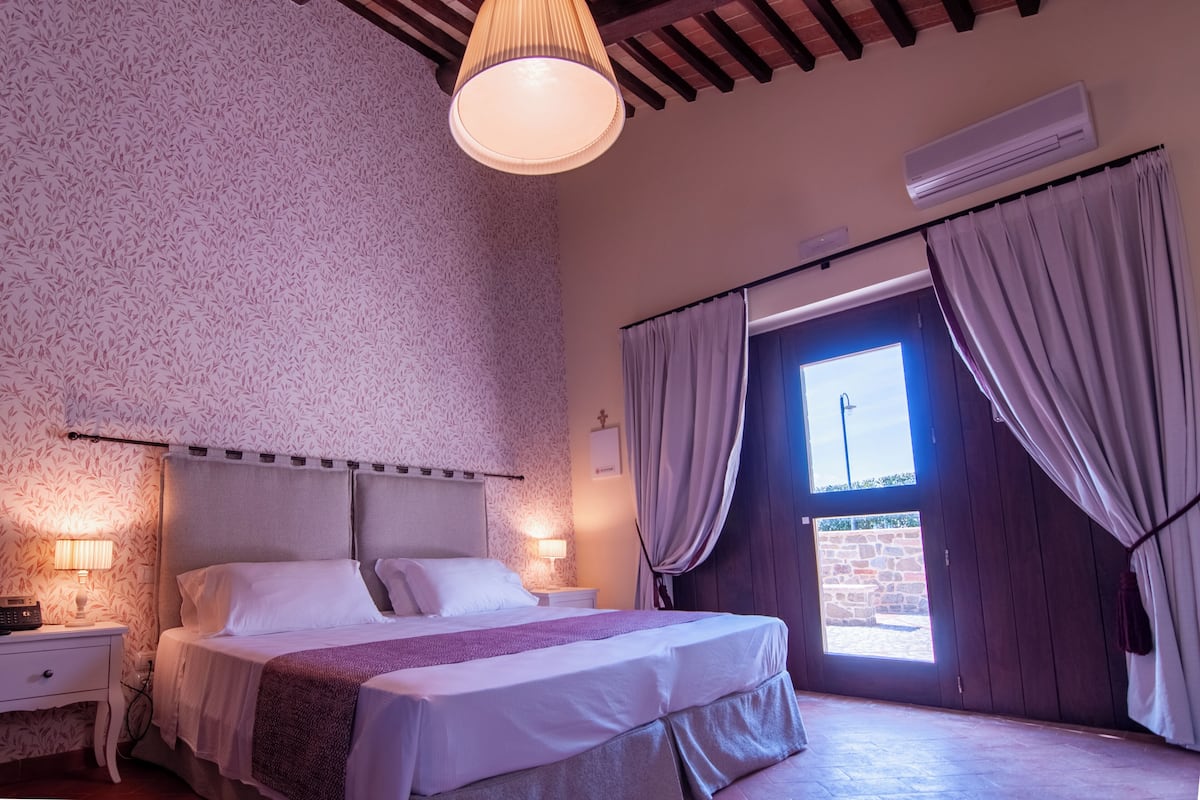 A bedroom with a bed, bedside lamps, a window with curtains, and a ceiling fan.