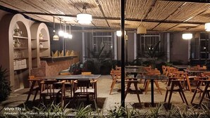 An outdoor dining area with tables and chairs, a covered seating area, and a view of the surrounding landscape.
