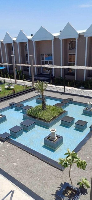 Una piscina con fioriere geometriche e una palma, circondata da un edificio dal design moderno.