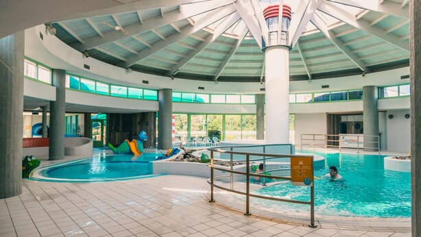 Une piscine intérieure dotée d’un plafond haut et de grandes fenêtres.