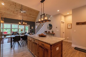 Una cocina moderna con una isla grande, armarios de madera y un ventilador de techo.