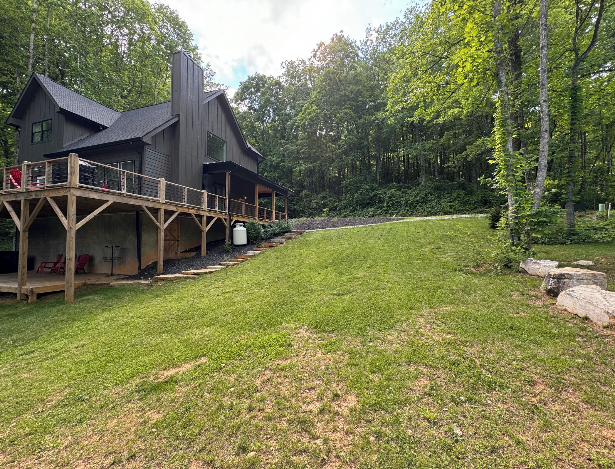 A modern house with a deck and a well-maintained lawn.