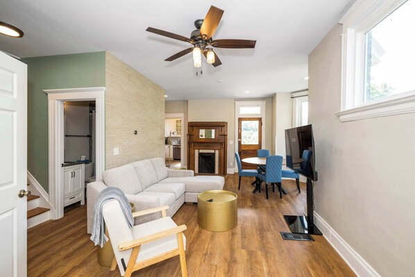 A living room with a sectional sofa, a coffee table, a TV, and a dining area with chairs. - Ludlow Lodge w/ City Views (Covington)