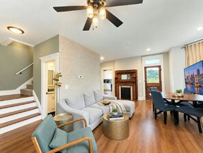 A spacious living room with a sofa, chairs, a fireplace, and a dining area. - Near Cincy Skyline Views Historic 4BR (Covington)