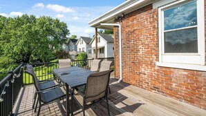A deck with a table and chairs, a brick wall, and a window. - Ludlow Lodge w/ City Views (Covington)