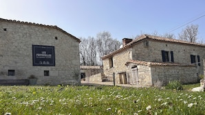 Un bâtiment en pierre sur lequel on peut lire l’inscription : « GÎTES LES FONTANELLES DU QUERCY BLANC ».