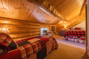 A cozy log cabin bedroom with a bed, a desk, and a chair. - Maggies Cabin w/ Boat Rental (Rexford)