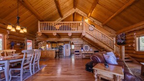 Ein geräumiges Blockhaus im Inneren mit Essbereich, Küche, Wohnzimmer und einem Balkon.