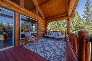Relax in a serene forest setting with a large window offering views of the surrounding woods, a cozy rug, and comfortable seating areas.