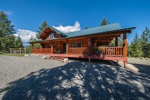 Set amidst evergreen trees, this cabin features a spacious porch and metal roof.