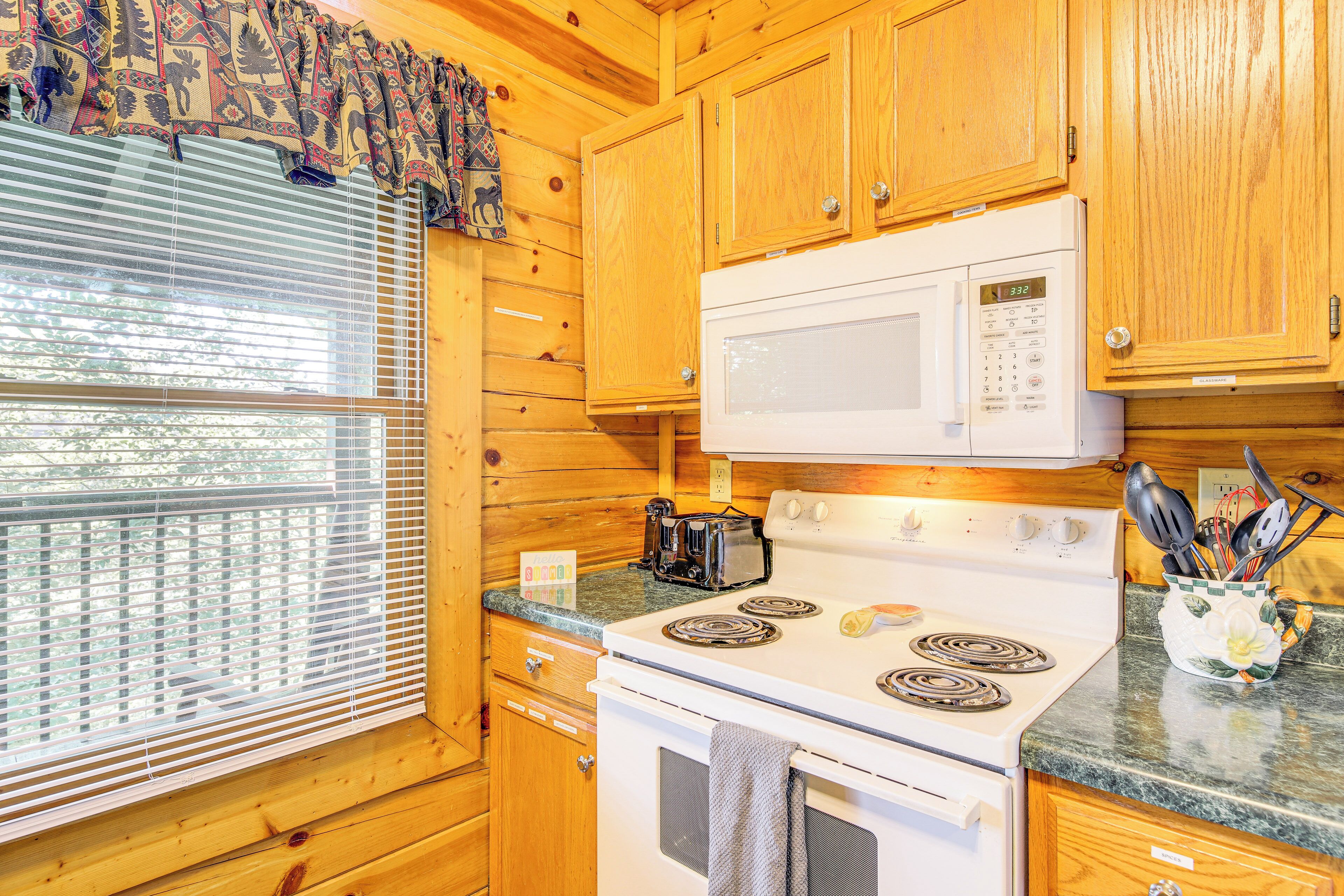 A kitchen with wooden cabinets, a white stove, a microwave, and a window with blinds.