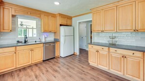 A kitchen with wooden cabinets, a white refrigerator, and a dishwasher. - Home w/ Fire Pit on 27 Acres in Walhalla! (Walhalla)