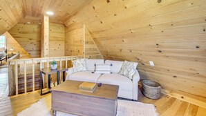 A cozy wooden cabin interior with a sofa, a coffee table, and a small table with a plant. - Home w/ Fire Pit on 27 Acres in Walhalla! (Walhalla)
