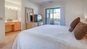 A bedroom with a large bed, a vanity with a mirror and lights, a television, and a sliding glass door to a balcony. - Sedona Condo on Golf Course w/ Pool Access! (Sedona)