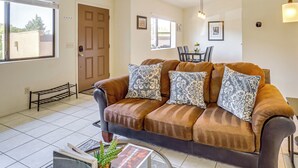 A living room with a brown sofa, patterned cushions, a glass coffee table, and a dining area with a table and chairs. - Sedona Condo on Golf Course w/ Pool Access! (Sedona)