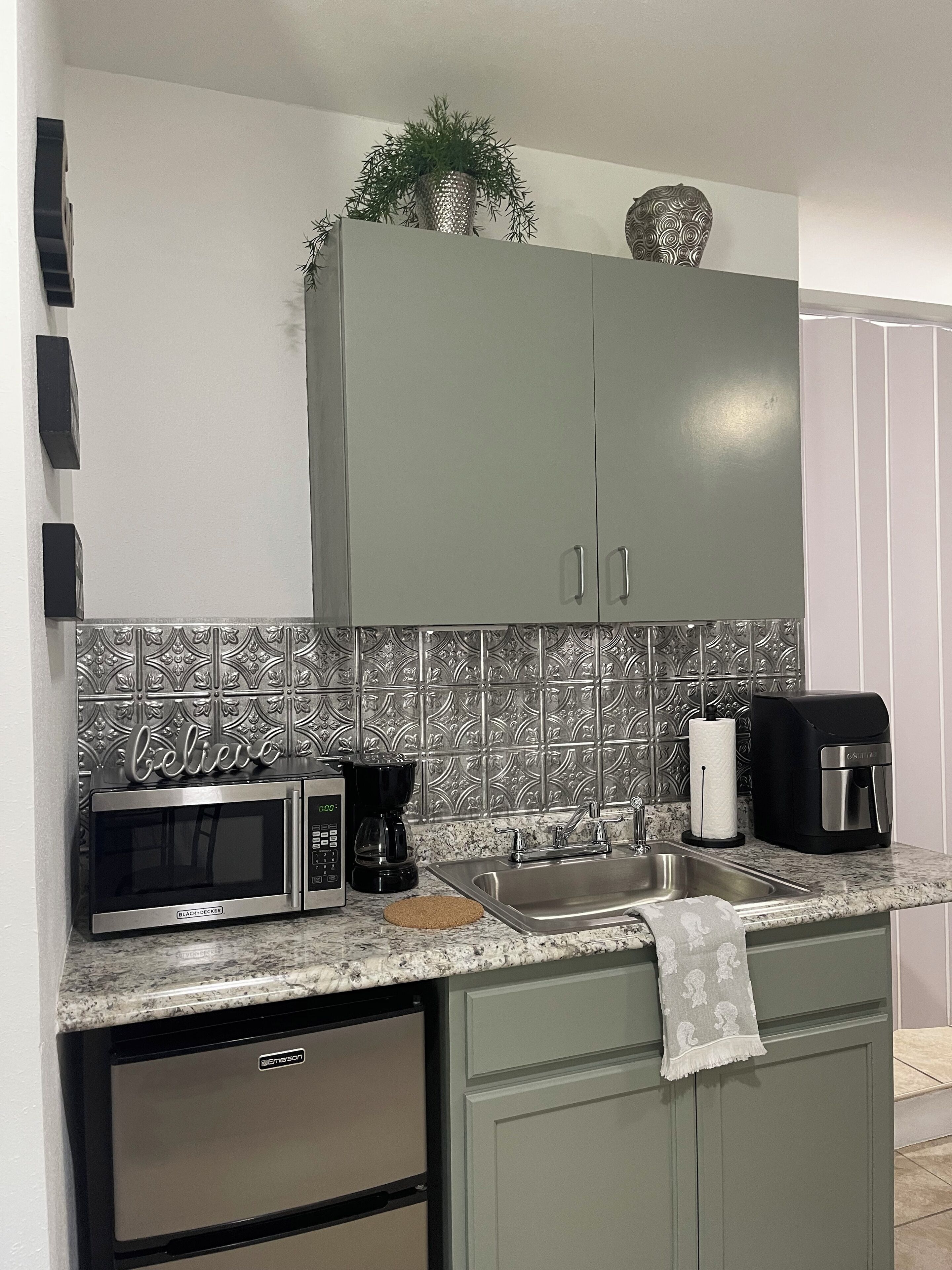 Una cocina con microondas, cafetera y pileta.
