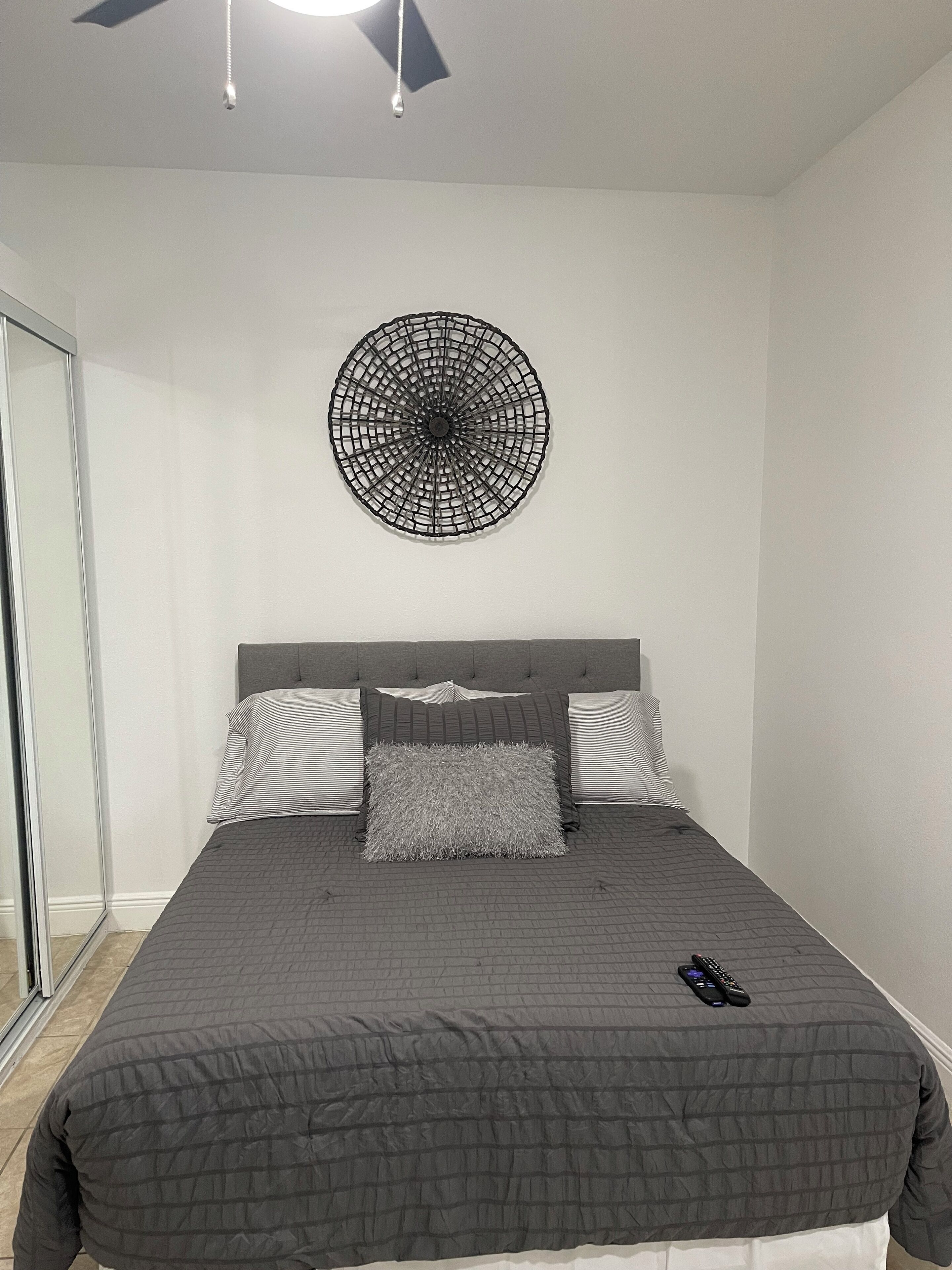 Een slaapkamer met een bed, een ronde wanddecoratie en een plafondventilator.