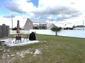 A backyard with a patio, outdoor furniture, a grill, and a white fence. - Cottage by the Sea- Short walk to the beach! (Mexico Beach)