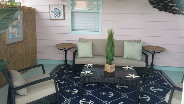Un coin salon confortable avec un canapé, deux petites tables d’appoint et une table basse décorée sur le thème de la marine.