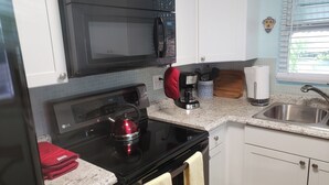 Une cuisine compacte équipée d’un four à micro-ondes, d’une cuisinière, d’une machine à café et d’un évier.