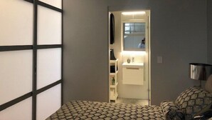 Ein schmaler Flur, der zu einem Badezimmer mit Spiegel und Waschbecken führt.
