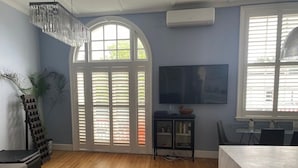 Un salon moderne doté d’un grand téléviseur, d’un coin repas et d’un escalier.