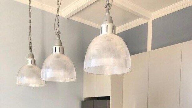 Une cuisine moderne dotée d’un îlot en marbre, d’appareils électroménagers en acier inoxydable, de luminaires suspendus et d’un bar pour prendre le petit-déjeuner.