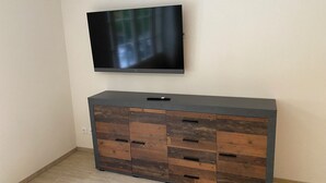 Ein modernes Wohnzimmer mit einem flachbildfernseher, der an der Wand über einem Holzkasten mit Metall und mehreren Schubladen angebracht ist.