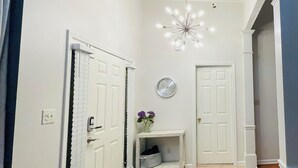 A hallway with a white door, a clock, a small shelf with a vase, and a doormat. - Cozy Retreats of the cove  (Jackson)
