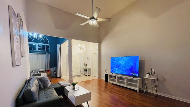 A modern living room with a flat-screen TV, a ceiling fan, and a dining area in the background. - Cozy Retreats of the cove  (Jackson)