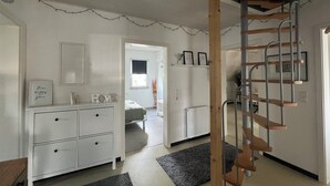 Een kamer met een witte dressoir, een houten ladder en een lijst met een afbeelding aan de muur.