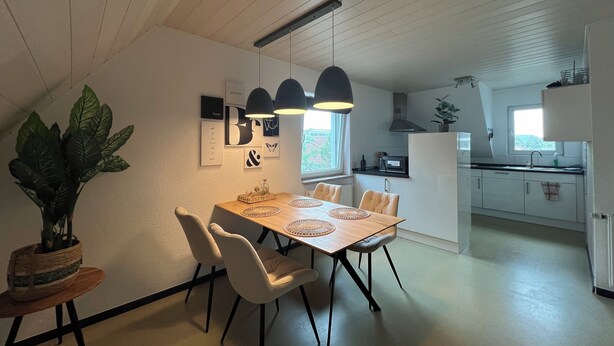 Een moderne keuken met witte kasten, een zwart aanrecht en een raam.