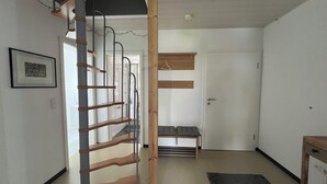 Een kamer met een houten trap, een bank en een deur.