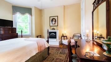 Une chambre à coucher comprenant un lit, une commode, une chaise, une cheminée et un grand miroir.