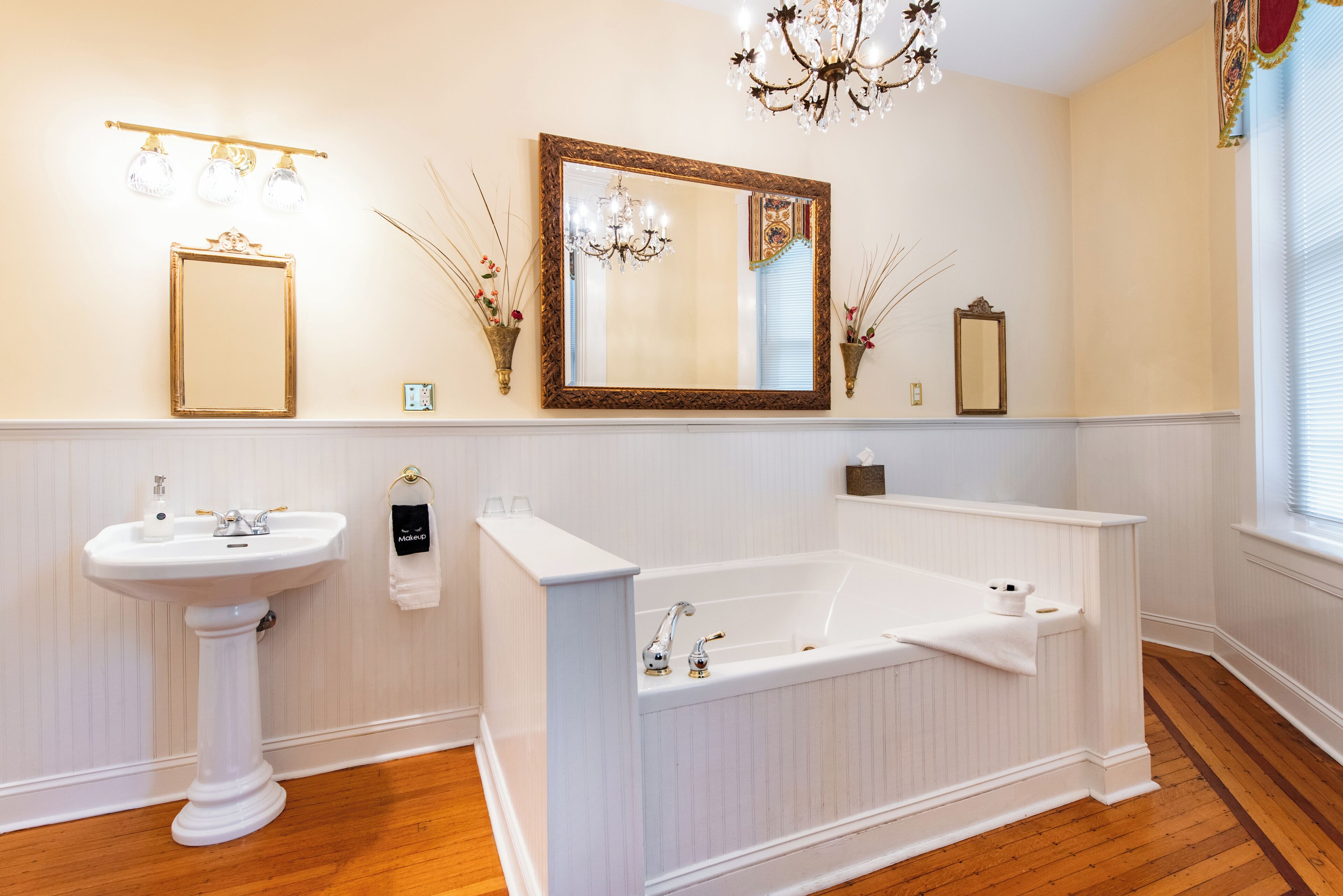 A bathroom with a pedestal sink, a freestanding bathtub, and a large mirror.